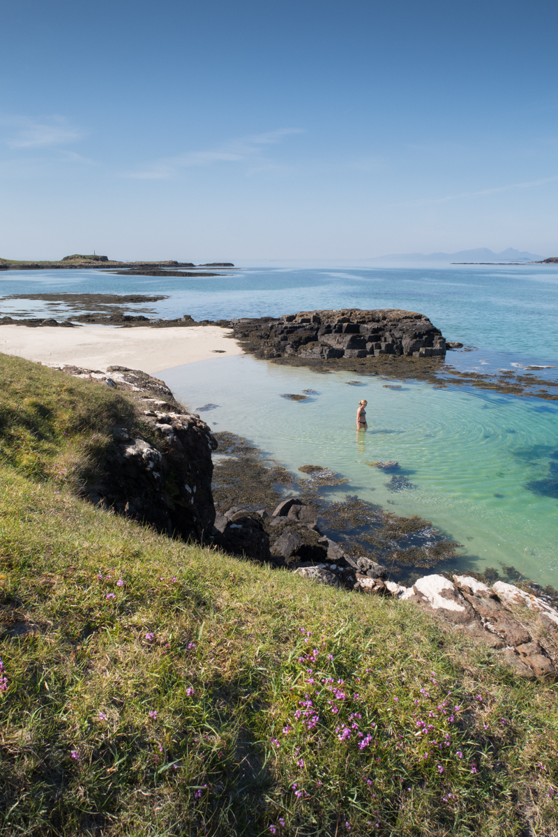 Wild swimmer enters the sea from a sandy cove at Croig between two rocky outcrops