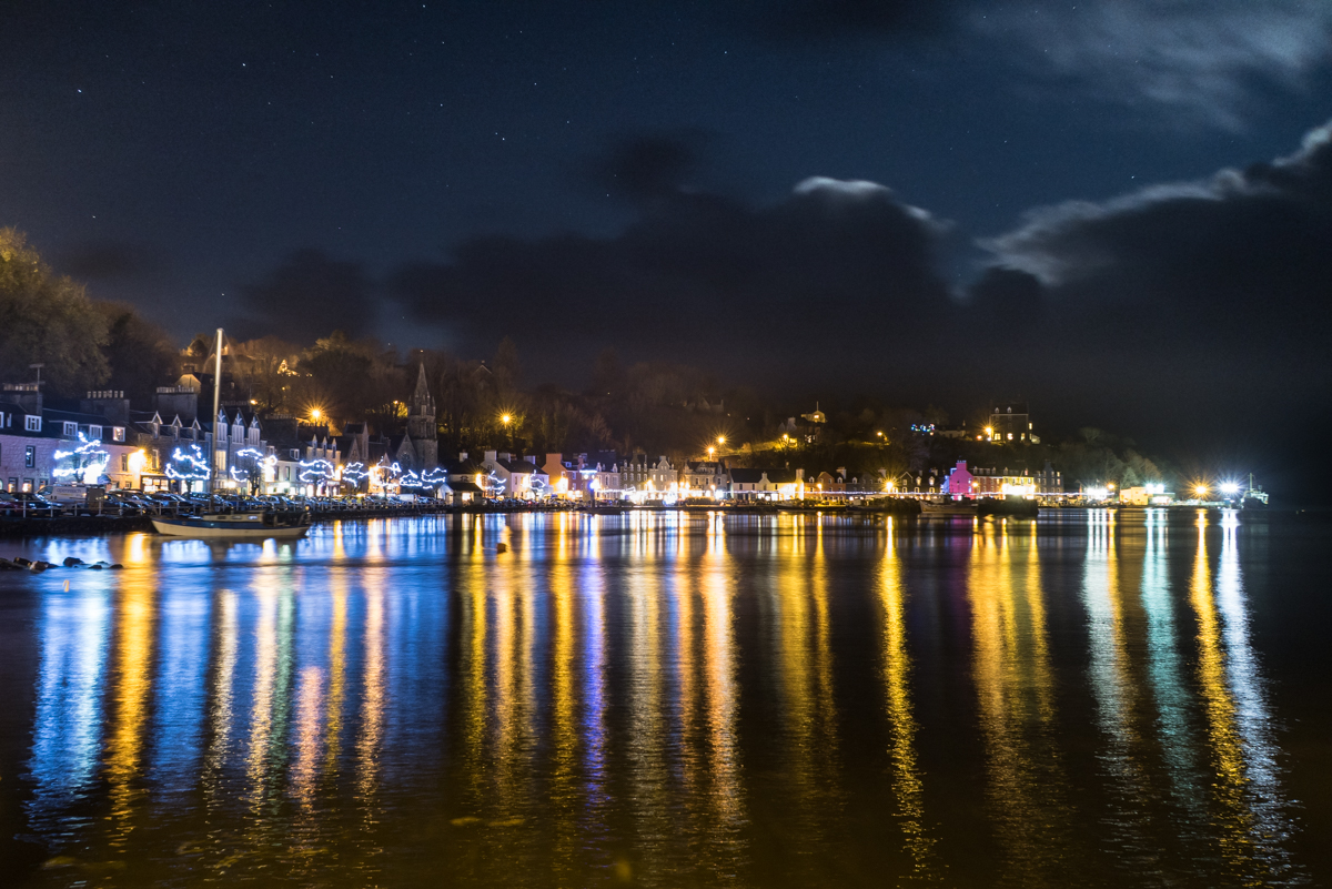 Christmas lights reflecting in the water at night along Tobermory harbour in winter