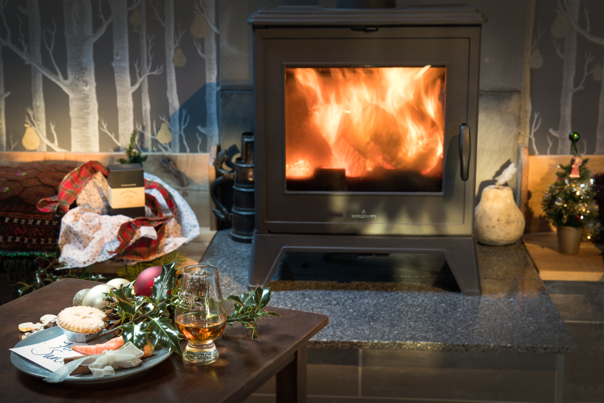 Roaring log burning fire at The Old Little Theatre holiday cottage on Mull with a plate of mince pies, glass of whisky and Christmas decorations