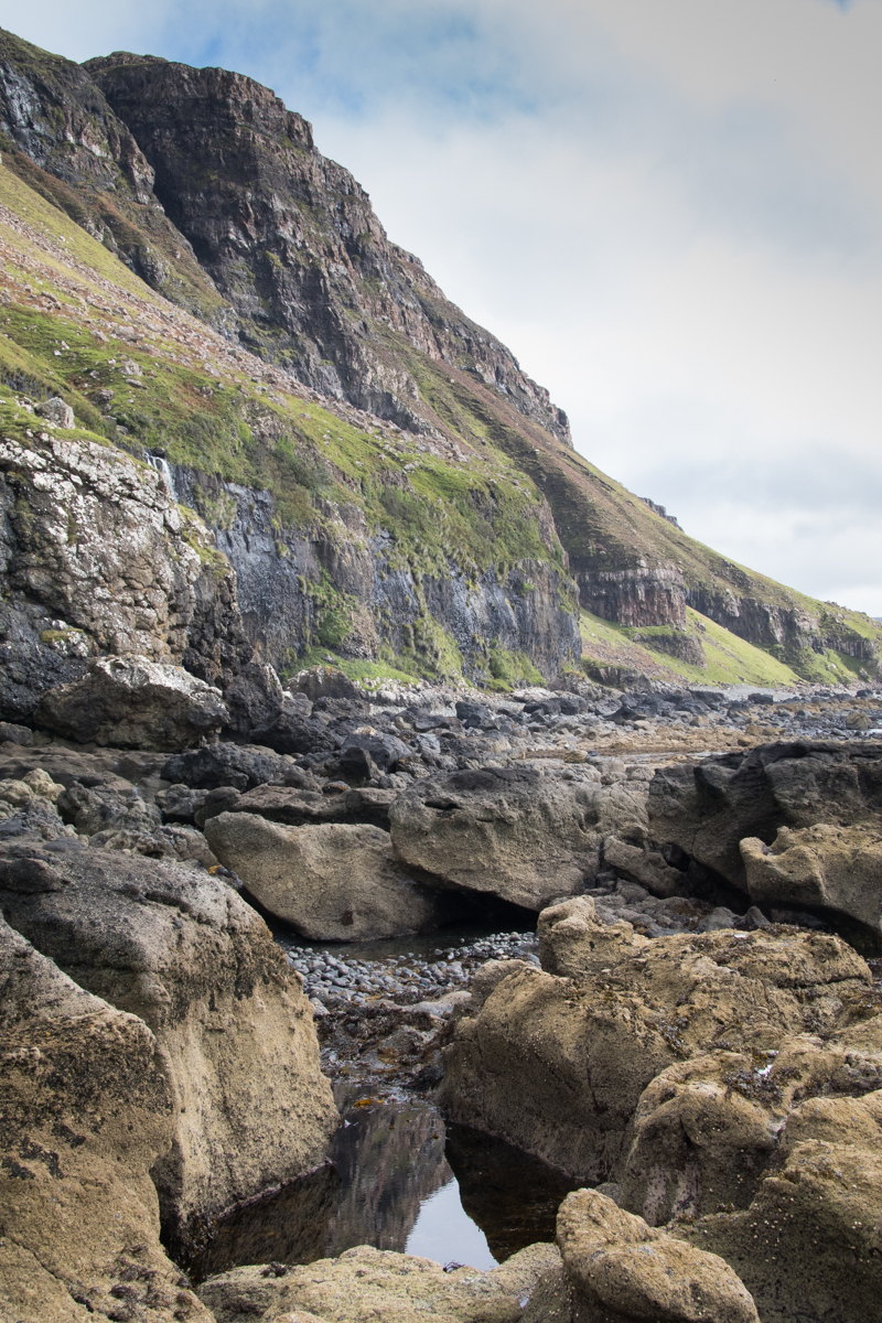 rocky shoreline with rock pool with large cliff towering above at Burg on Mull