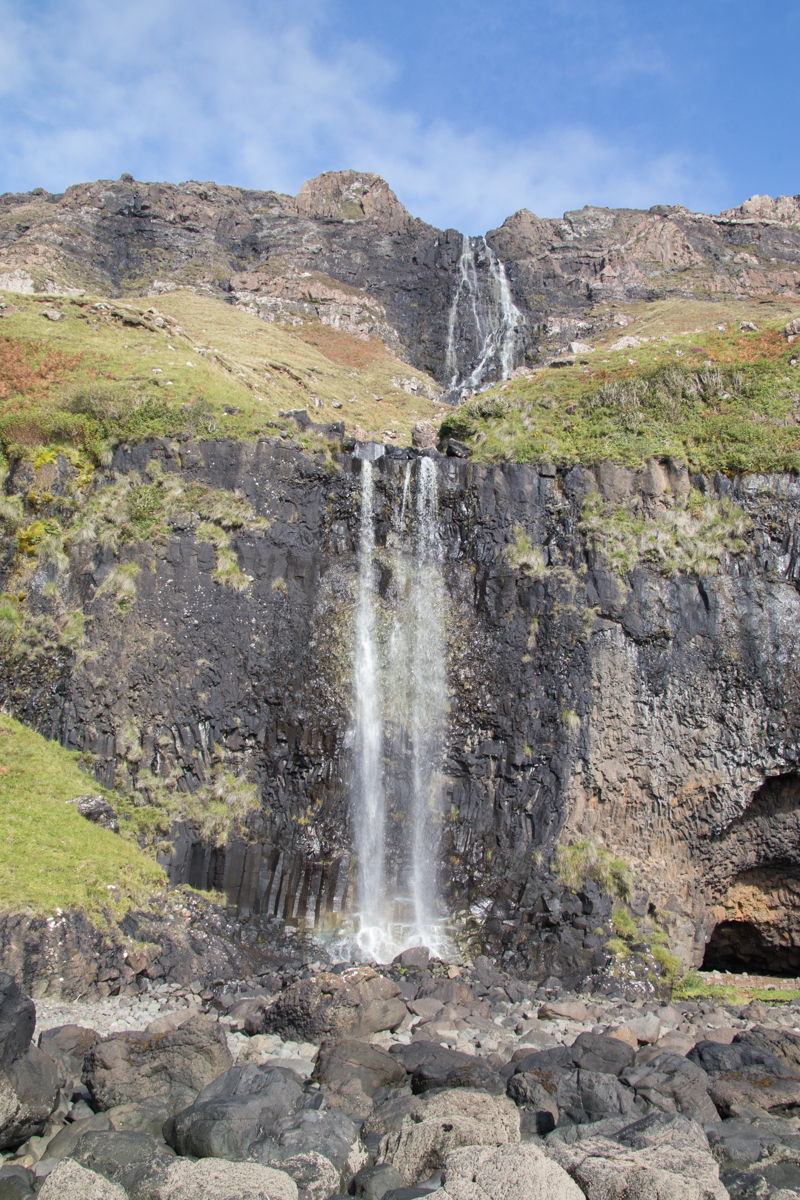 Waterfall cascading down lush green and rocky cliffs on Ardmeanach peninsula, Isle of Mull