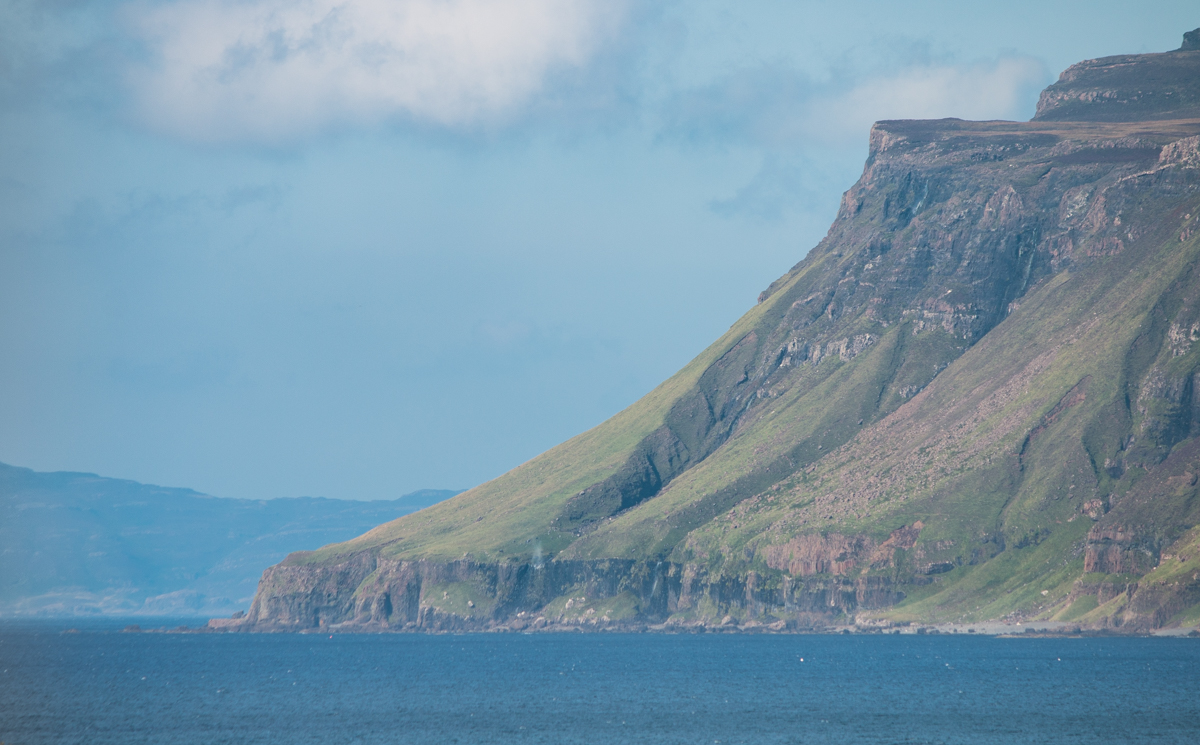 Ardmeaneach peninsula wilderness headland meeting the sea at Loch Scridain with steep cliffs and blue skies above