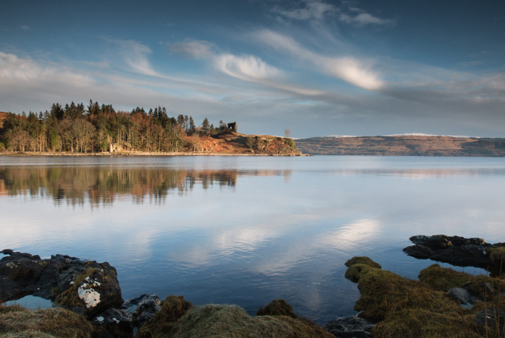 The ruins of Moy Castle standing on the forested hill overlooking the Aros Estuary and out to Salen Bay on the Isle of Mull