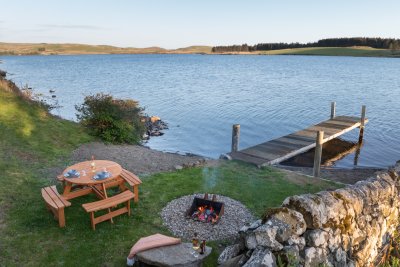 The garden area at Assapol Lodge with pier, fire pit and picnic bench