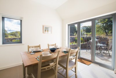 Dining table with double doors leading to patio area