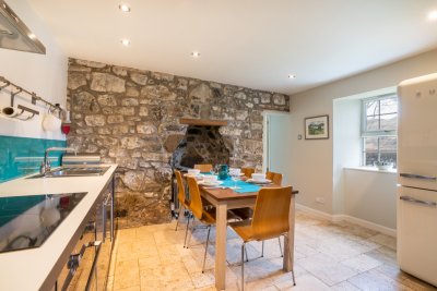 The quaint kitchen has a rustic feel with exposed stone and vintage-style Smeg fridge freezer
