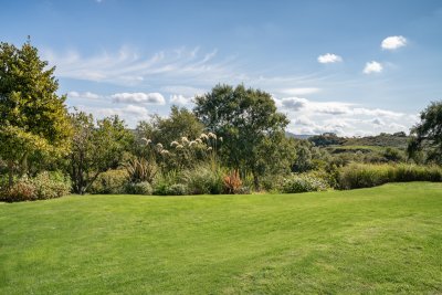 The well-tended garden includes lawn, shrubs and lovely views