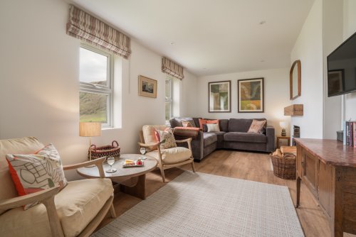 Relax in the cosy living room at Carsaig Cottage East, with wood burner and sea views