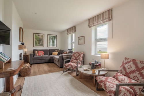 The spacious living room feels very inviting with cosy finishing touches